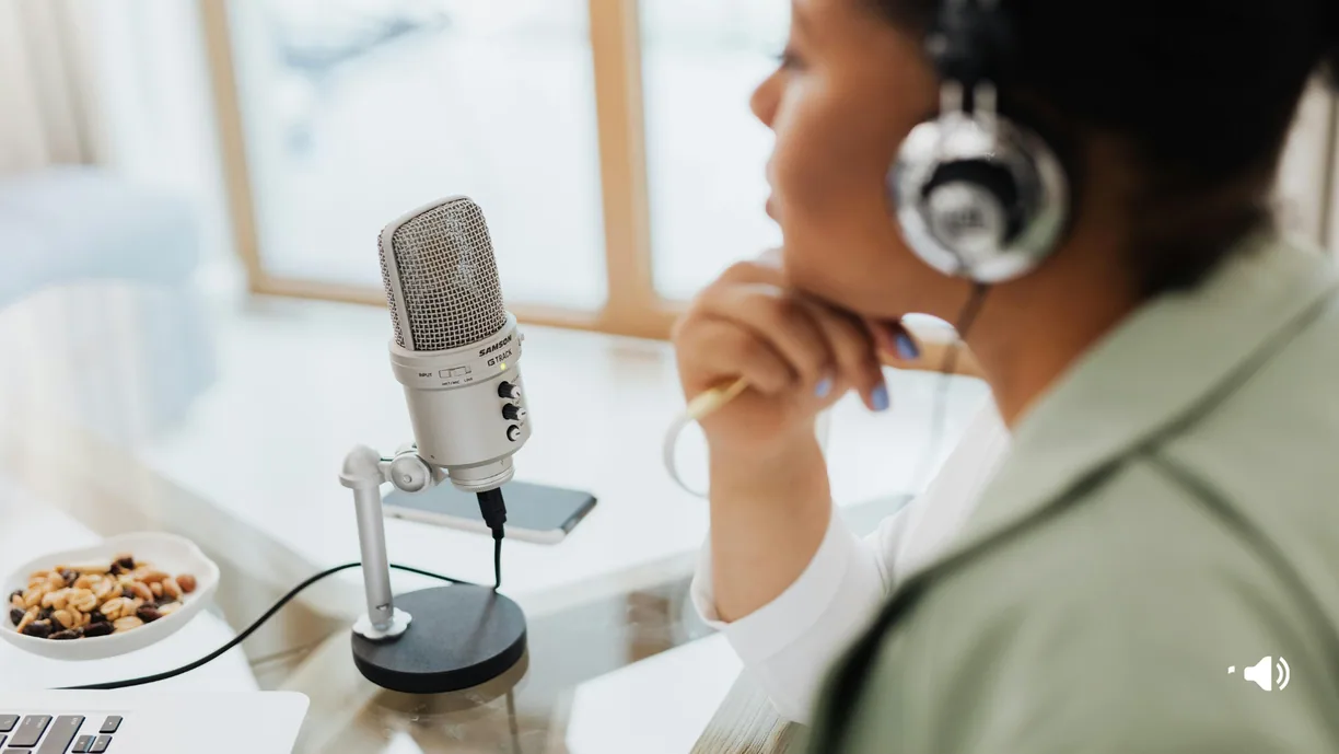 Presenter with headphones recording at a studio microphone.