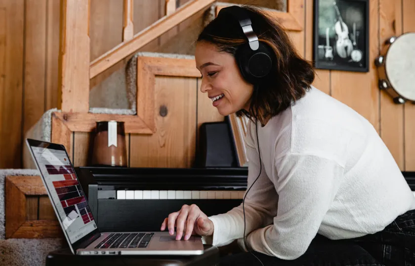 A woman wearing headphones uses a laptop to decide on assistive technology: ReadSpeaker Text to Speech, free TTS, or both?