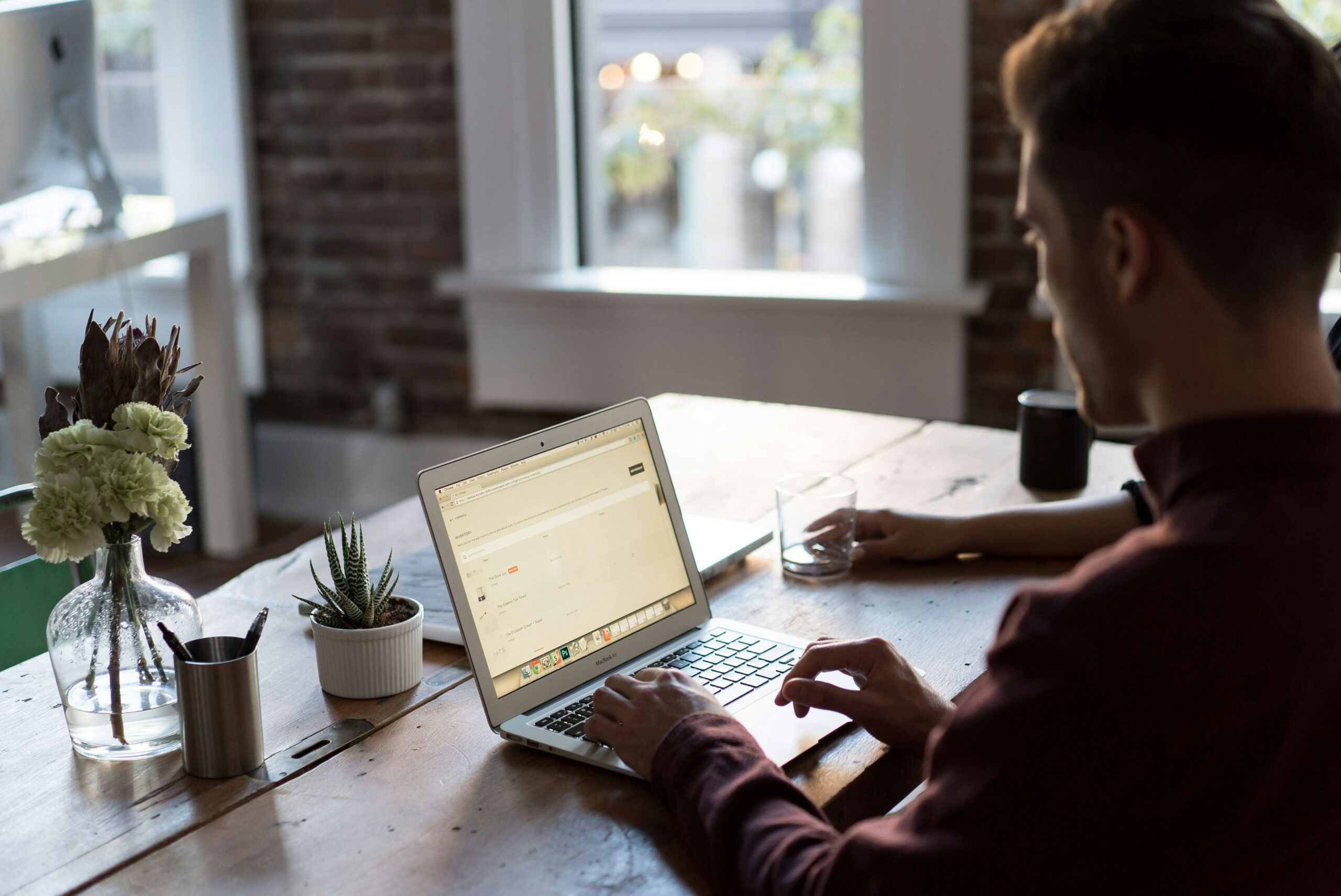 Man operating laptop on top of table.